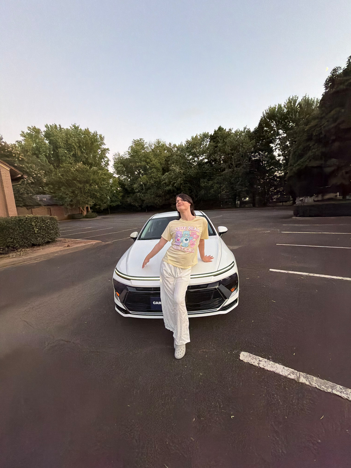 Joseph standing in front of his white car at dusk