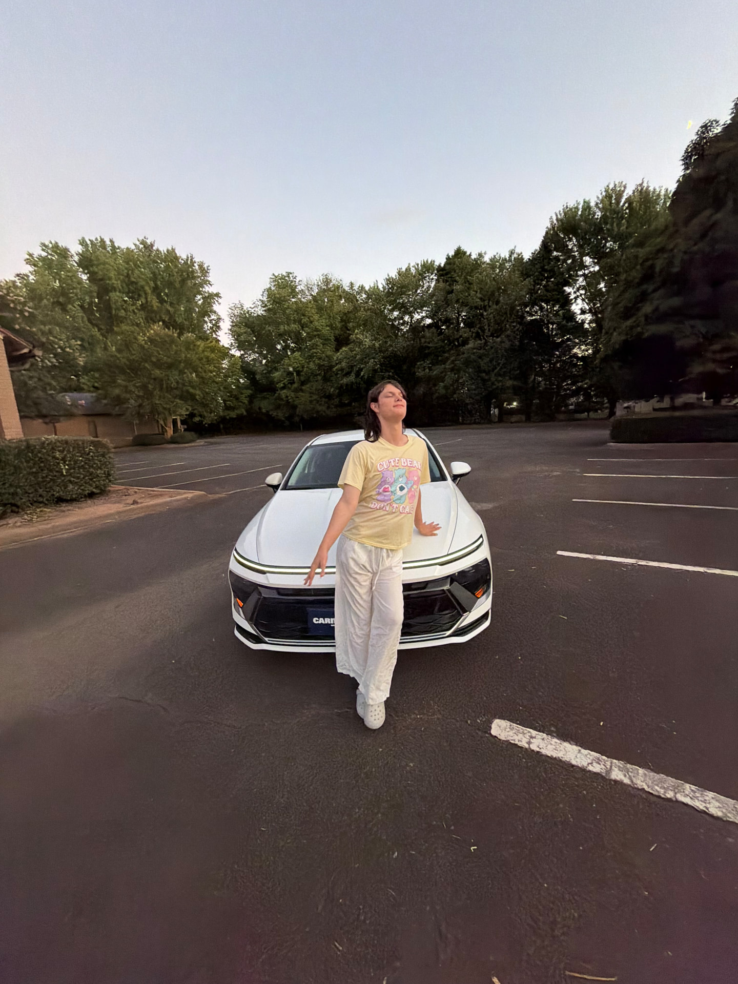 Joseph leaning on his white car in a parking lot